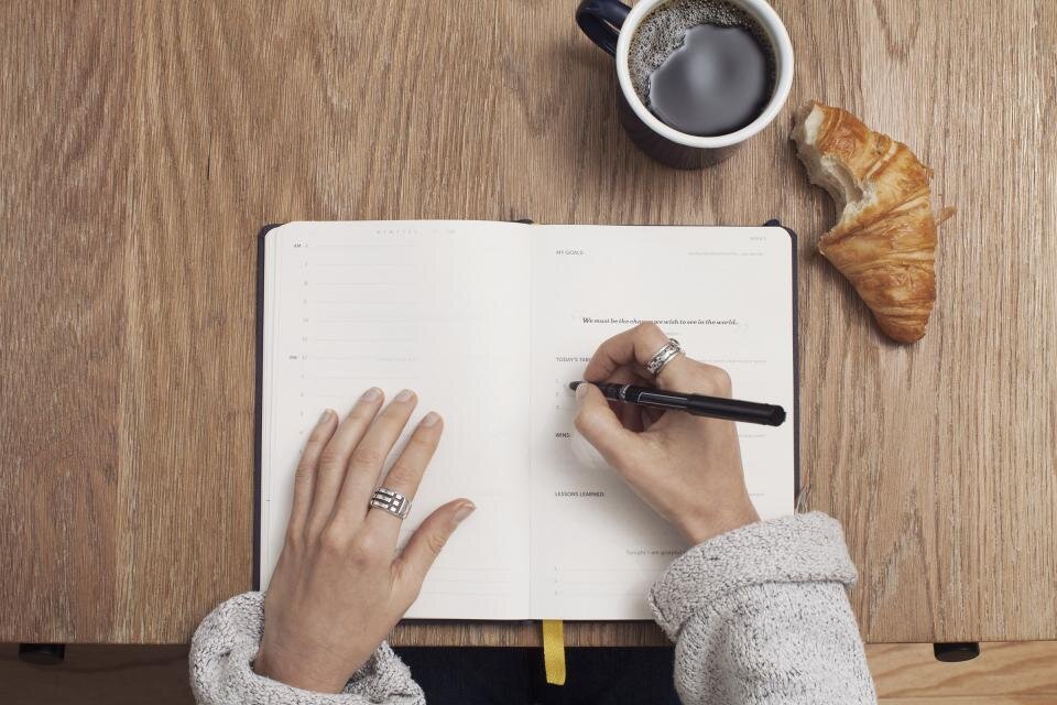 An open notebook beside a cup